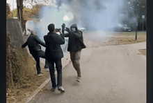 Група људи на улици са смеђом балонима димом у позадини.