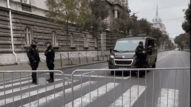 Вид блокиране улице са металним барикадама и полицијским службеницима.