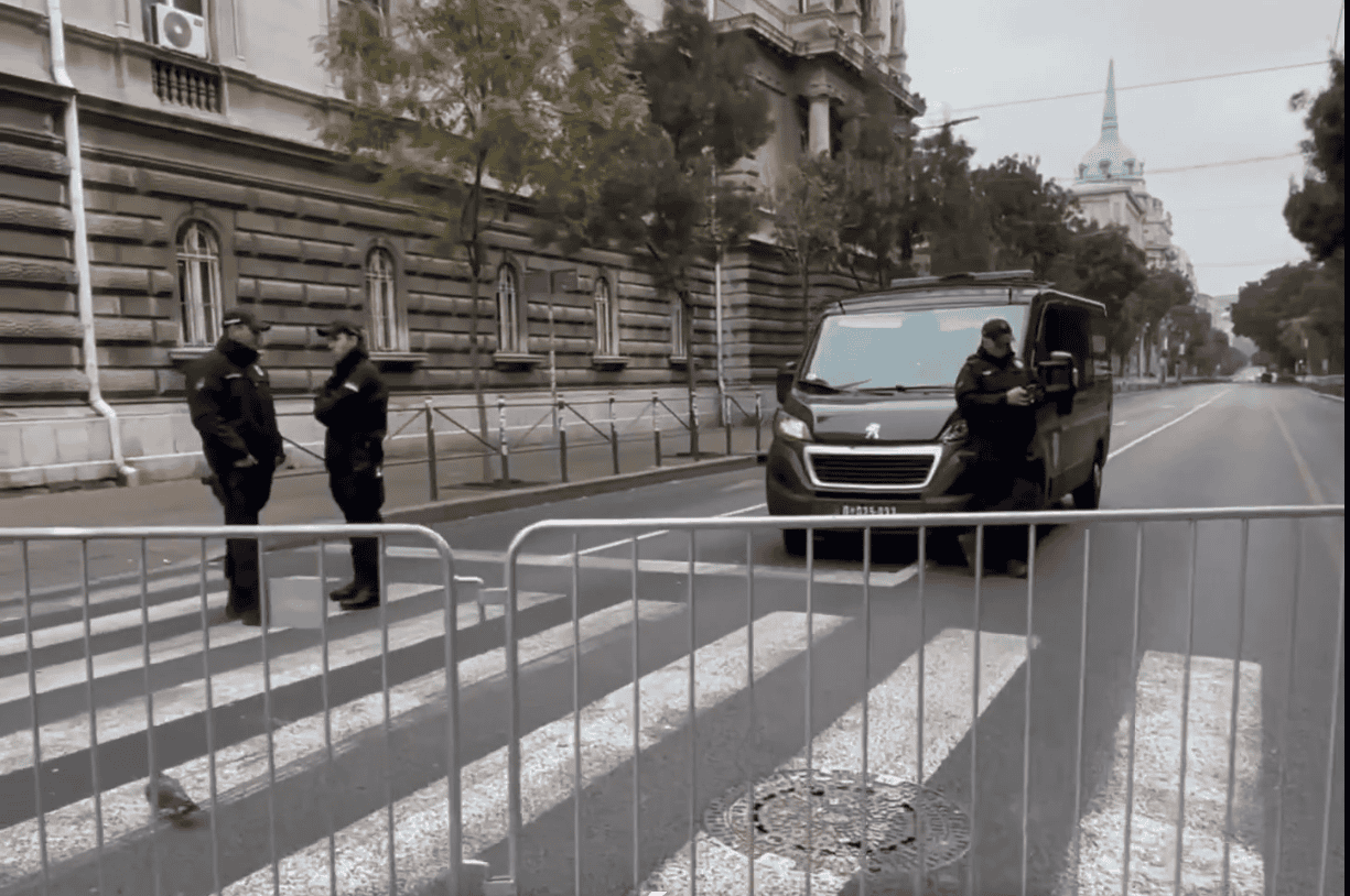 Вид блокиране улице са металним барикадама и полицијским службеницима.