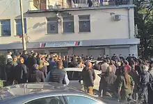 Група људи који се окупила испред зграде саводоградном надзором.