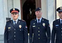Три полицијска службеника стоје испред зграде.