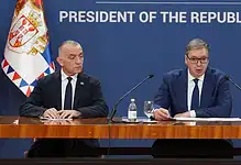 Двојица званичника на конференцији са застава Србије у позадини.