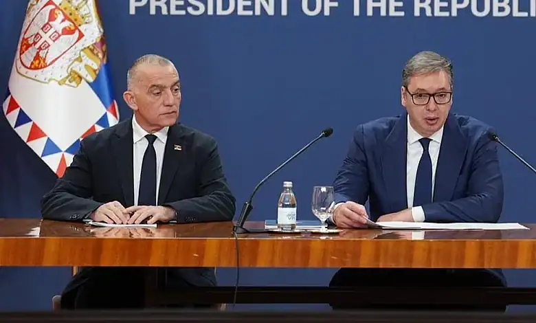 Двојица званичника на конференцији са застава Србије у позадини.
