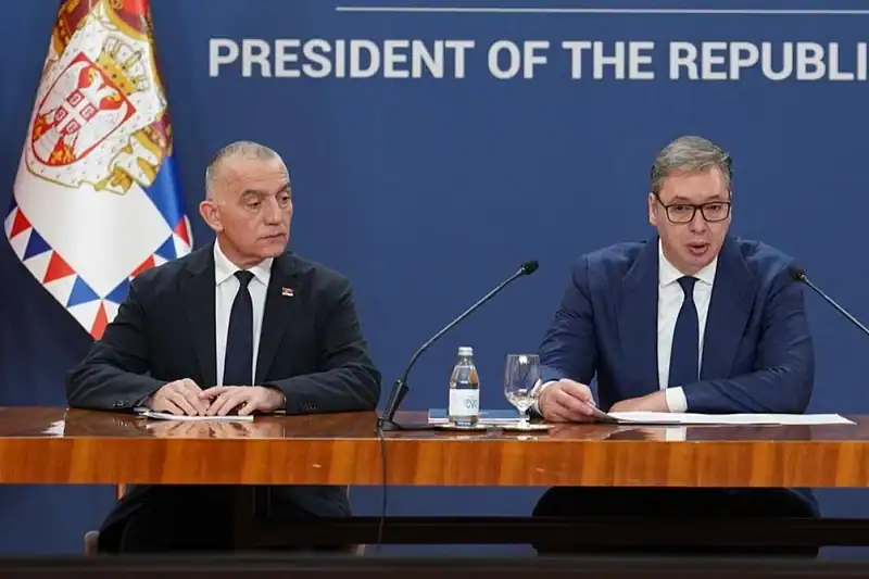 Двојица званичника на конференцији са застава Србије у позадини.